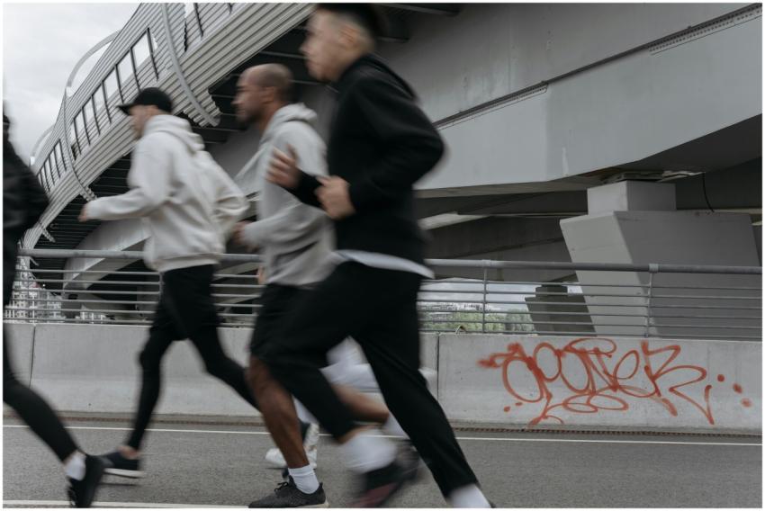 A group of people jogging briskly under an urban h