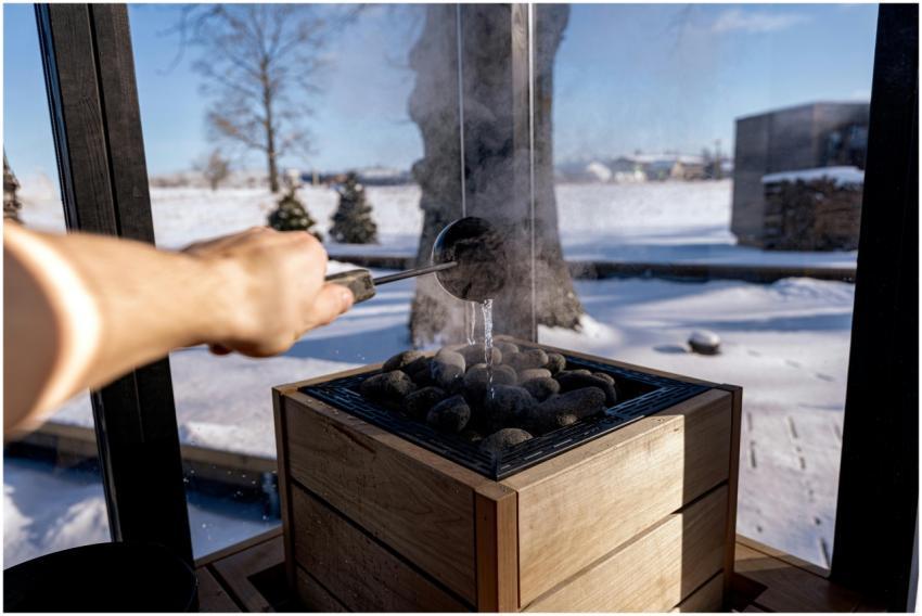 Steam rises from sauna stones as water is poured i