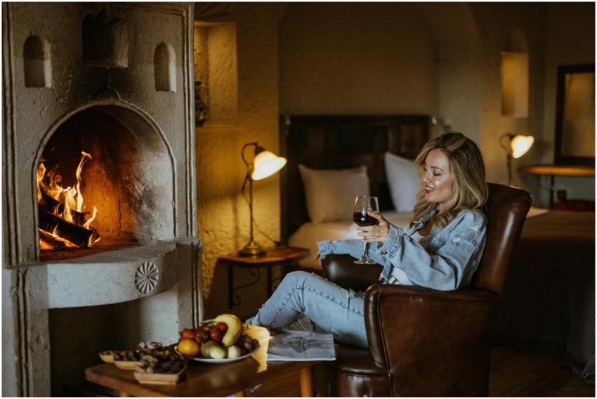 A woman enjoying wine in a cozy room with a firepl