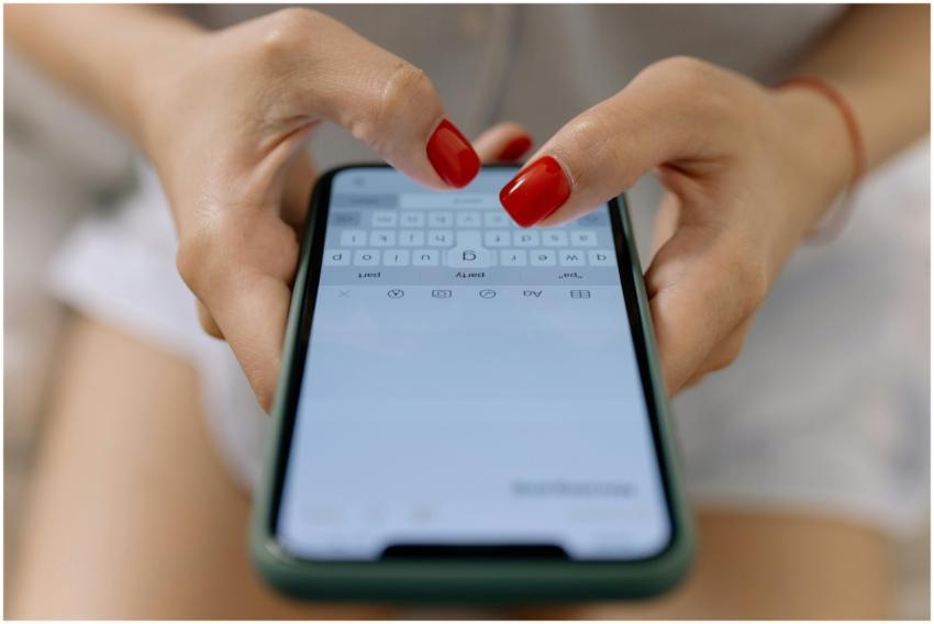 Close-up image of hands with red nails typing on a