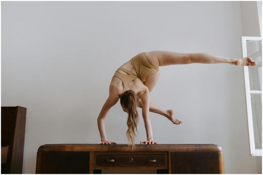 A flexible gymnast in a handstand poses indoors, s
