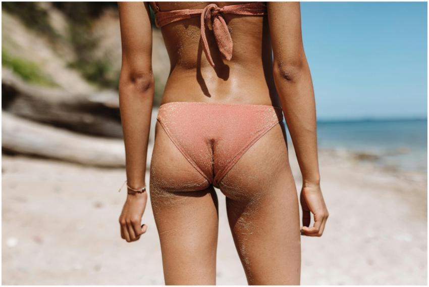 A back view of a woman in a bikini enjoying a sunn