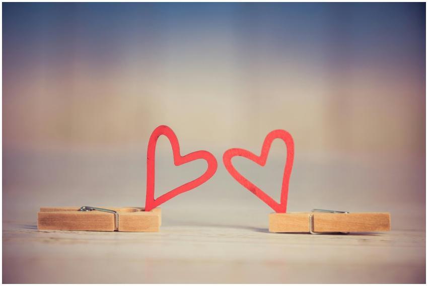 Two wooden clothespins with red heart shapes, symb