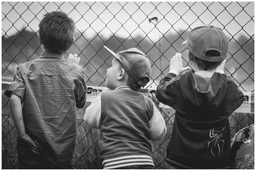Black and white image of three young boys peering
