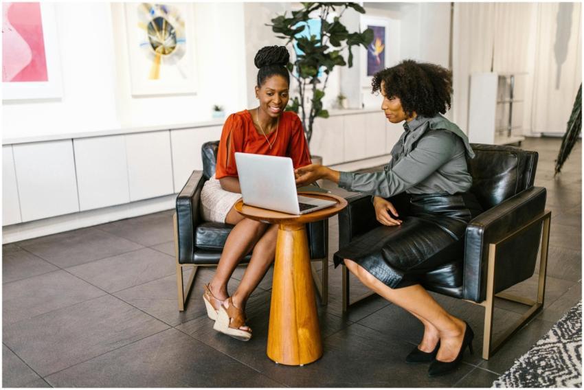 Two women collaborate on a project using a laptop