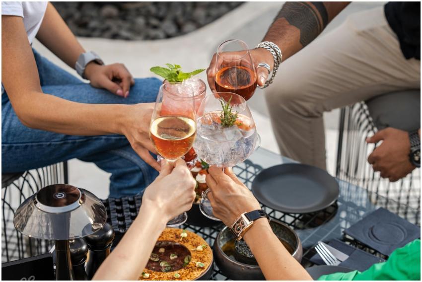 Four friends clinking glasses at an outdoor gather