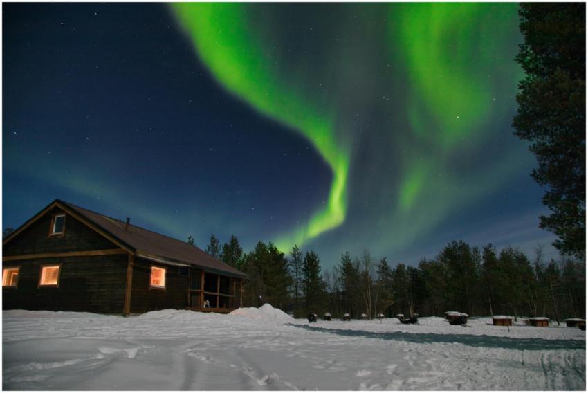 Enchanting northern lights over a snowy cabin in K