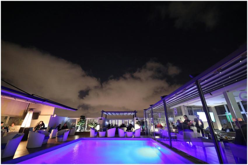 A vibrant rooftop lounge with a glowing pool under