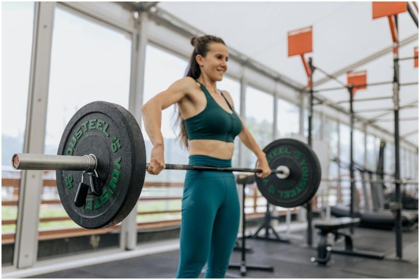 A fit woman lifting a heavy barbell at an indoor g
