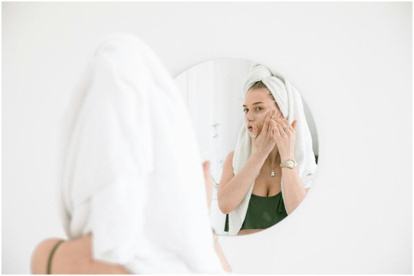 A woman applies face cream in the bathroom, reflec