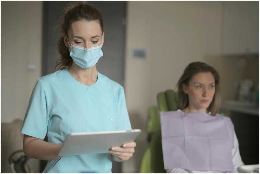 Dentist with mask consulting a patient using a tab