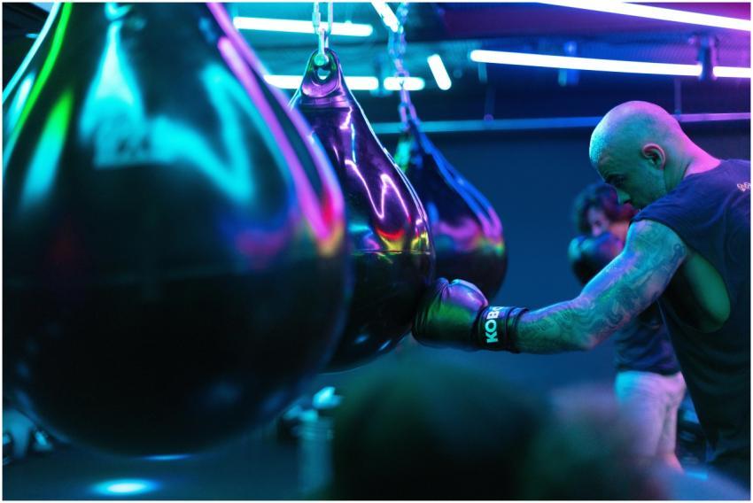 A boxer practices punches with neon-lit punching b