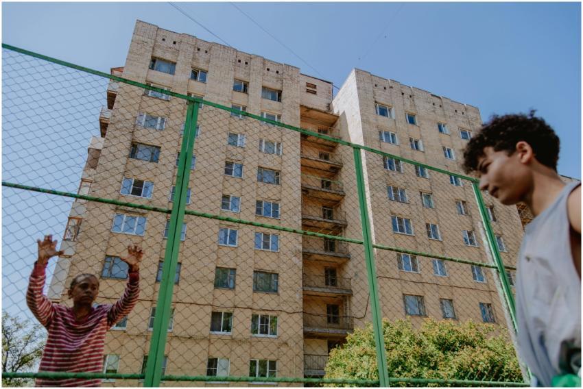 Two teenagers interact at an outdoor sports ground