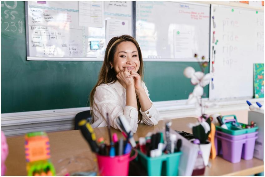 Cheerful teacher sitting at a desk in a bright cla