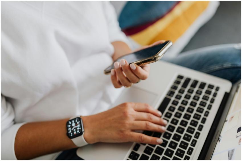 Close-up of a person using a smartphone and laptop