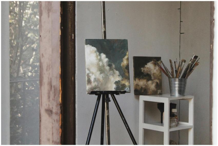 Cozy art studio featuring cloud paintings on easel