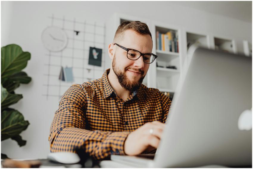 A confident man with glasses working on a laptop i