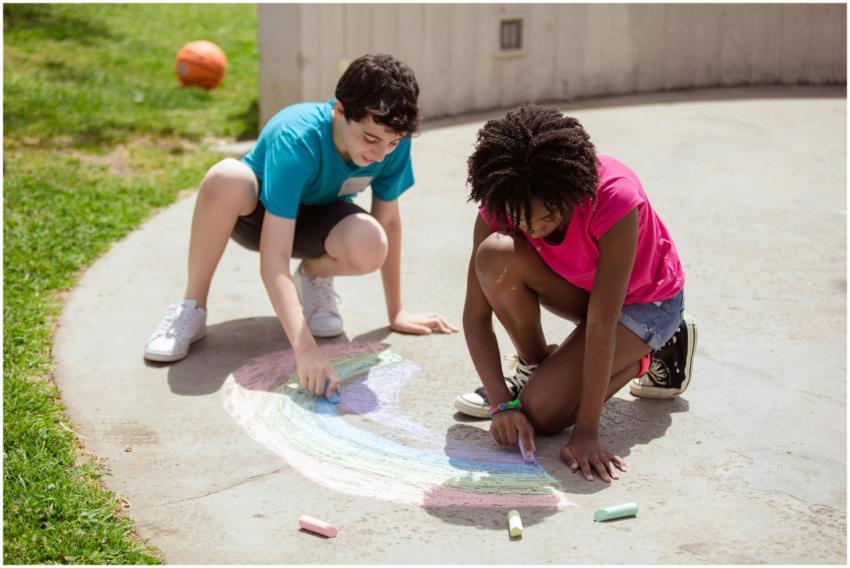 Two kids drawing with colorful chalks on a sunny d