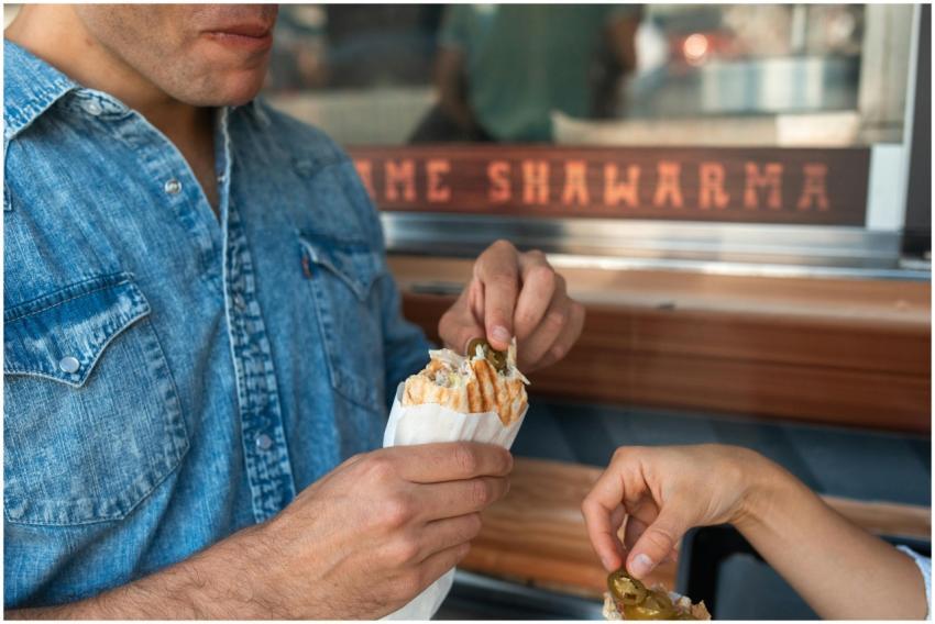 A close-up of two people enjoying shawarma from a