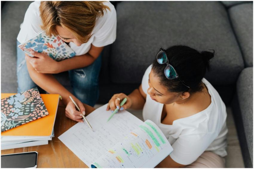 Two women collaborating on study notes in a cozy i