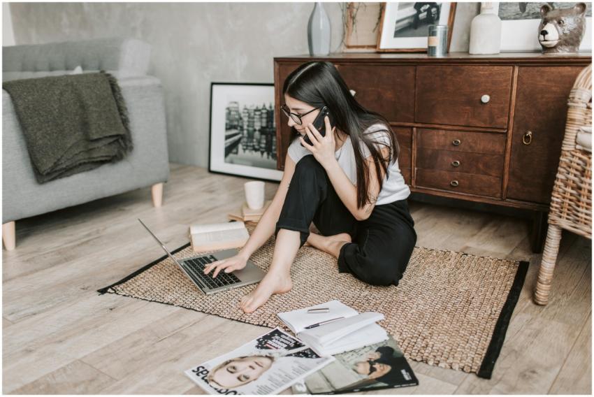 Young woman working from home, balancing laptop an