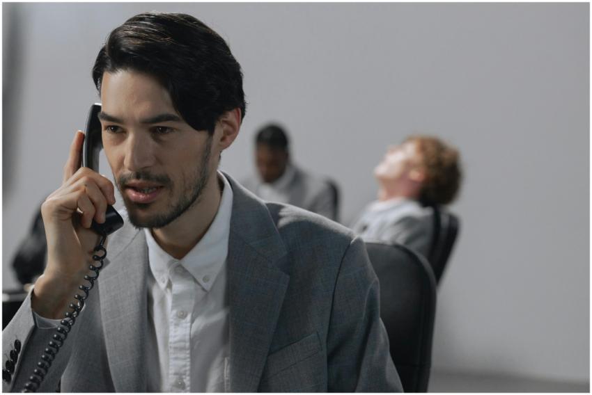 Young businessman in gray suit on phone, emphasizi