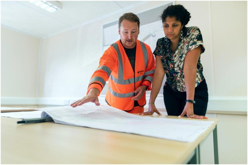 Two engineers reviewing blueprints in an office, d