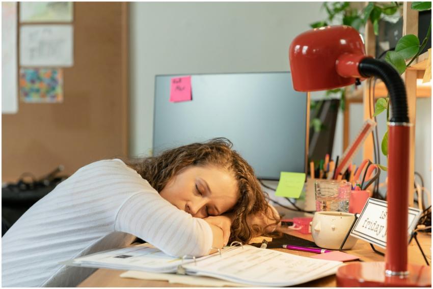 A woman sleeping at her office desk, surrounded by