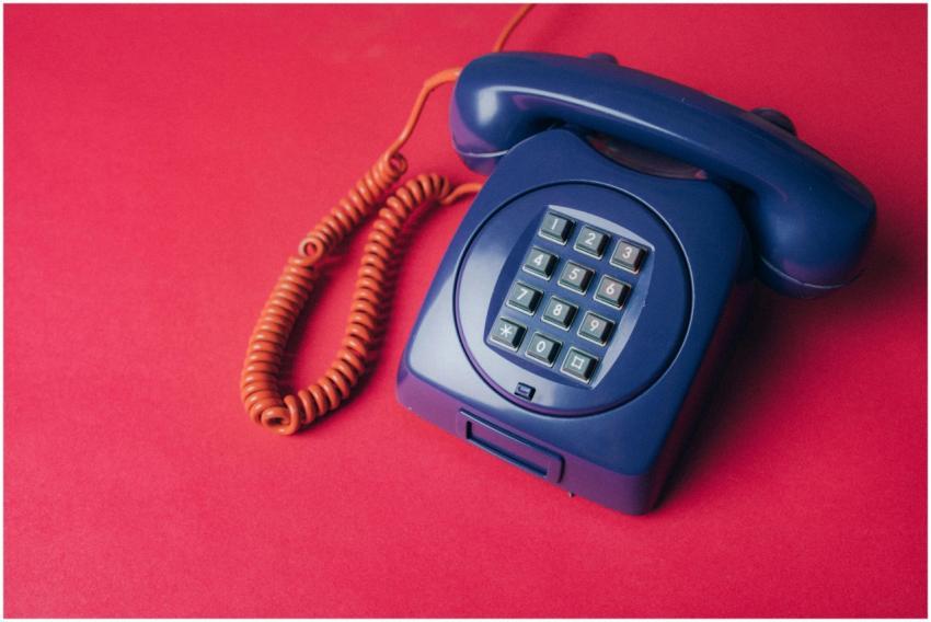 A classic blue rotary phone with a coiled cord on