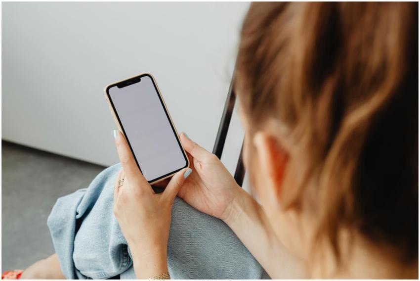 A woman holds a smartphone with a blank screen ind