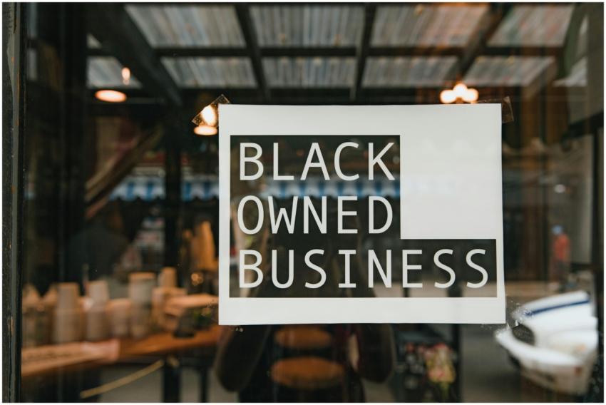 Black owned business sign taped on a window, seen