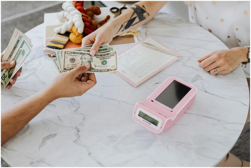 Close-up of hands exchanging US dollars over a mar
