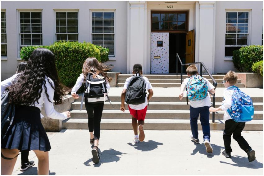 Group of students with backpacks running into scho