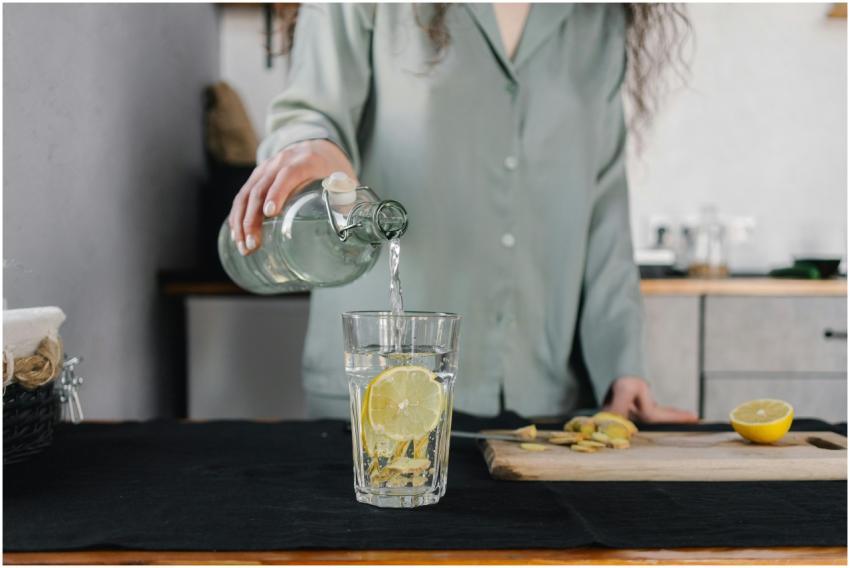 Woman pours water for lemon ginger infusion, promo