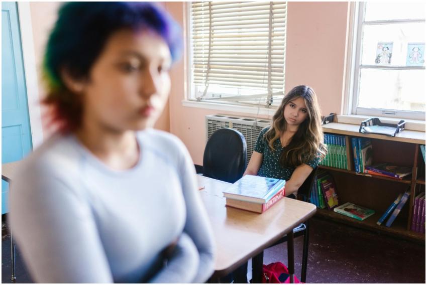 Two teenage girls in a classroom setting, one focu