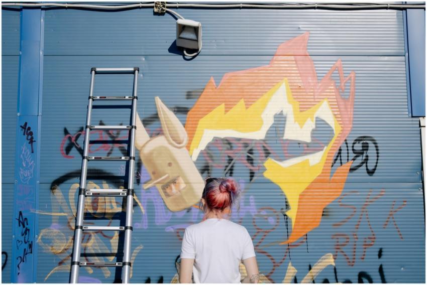 Street artist with vibrant hair painting graffiti