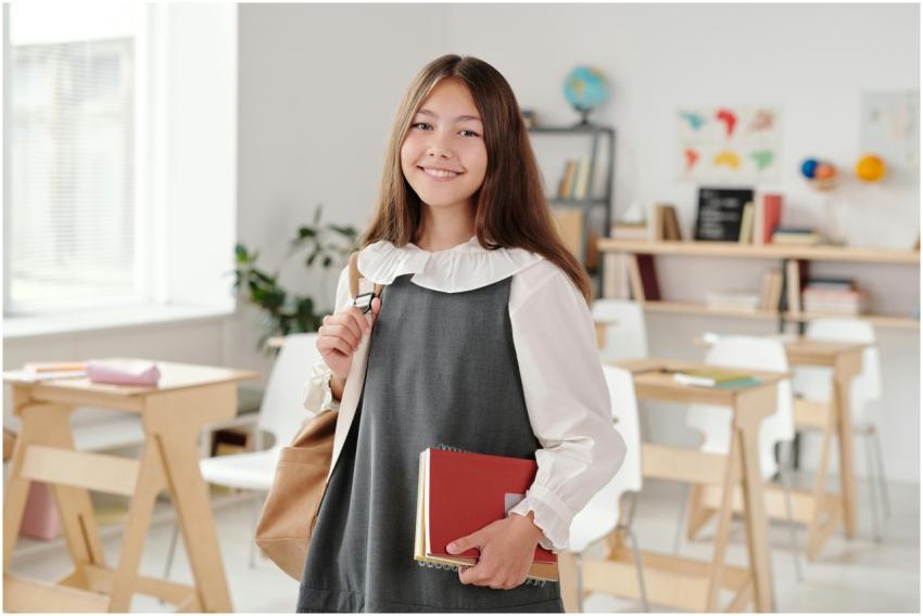 Smiling teenage girl in a school uniform holding n
