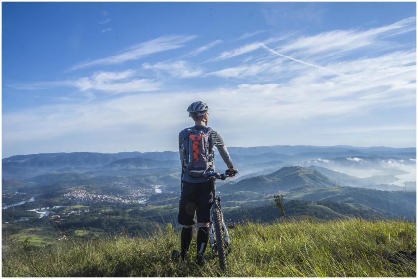 A cyclist stands on a hill, gazing at a stunning m
