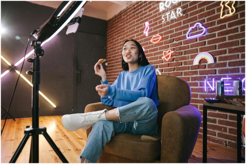 Young Asian woman streaming live indoors with neon