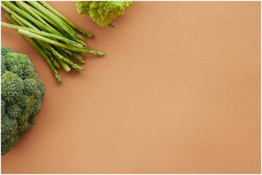 Asparagus and broccoli on brown surface with ample
