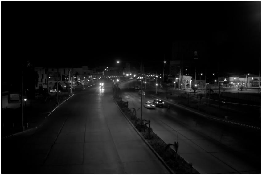 A night view of a bright urban street with cars an