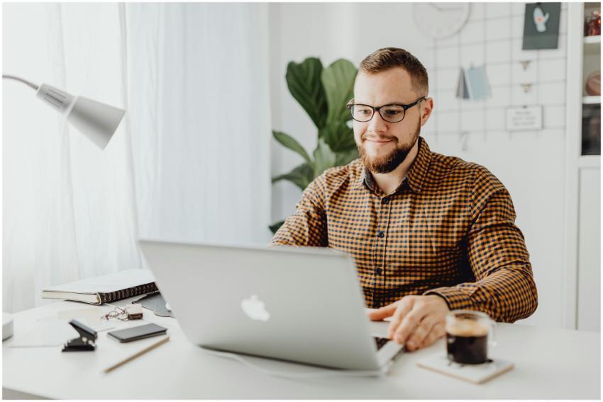 Adult man with eyeglasses typing on a laptop in a