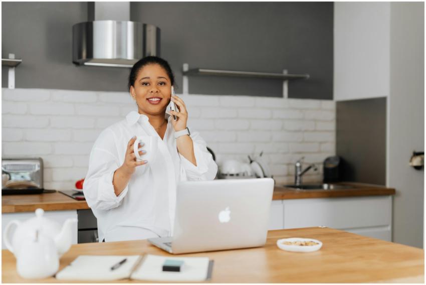 Confident woman multitasking with phone and laptop