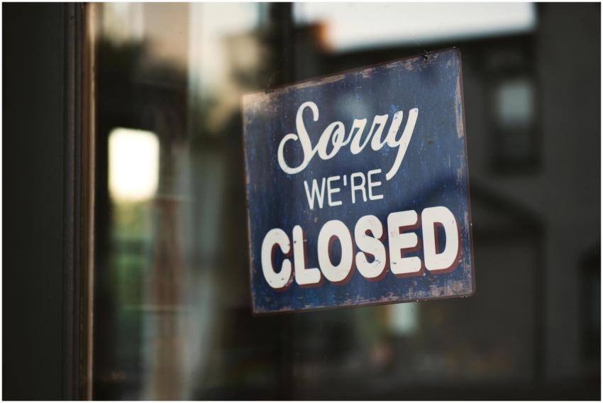 A vintage "Sorry We're Closed" sign on a glass doo