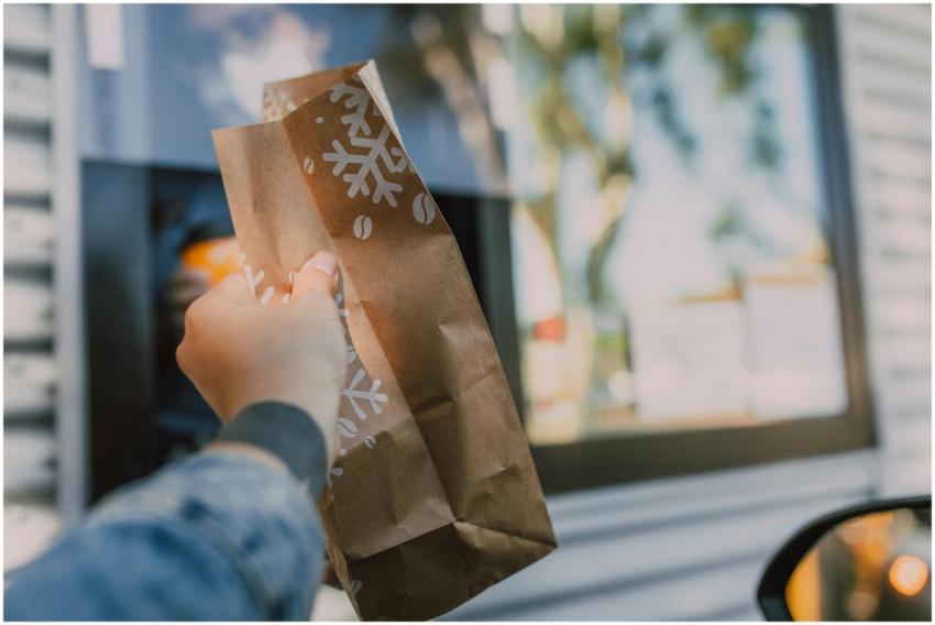 Hand reaching out with brown paper bag at drive-th