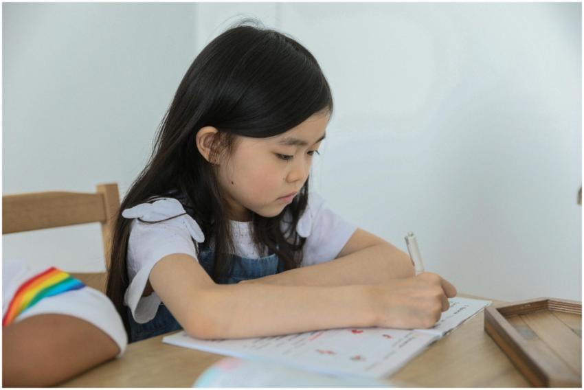 Concentrated ethnic schoolkid writing in activity