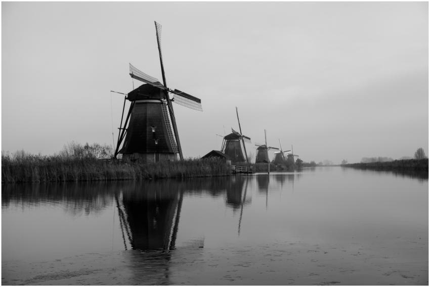 Black and white photo of iconic windmills reflecti