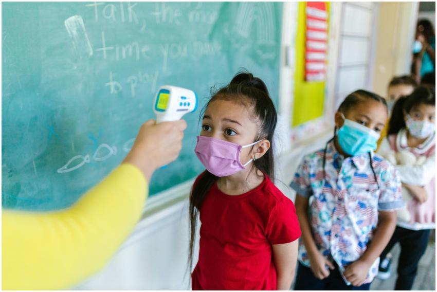 Children wearing masks have their temperature chec