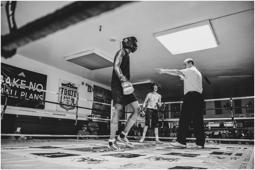 Black and white photo of a boxing match with a ref