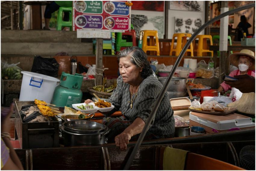 Elderly woman cooking traditional Thai dishes at a